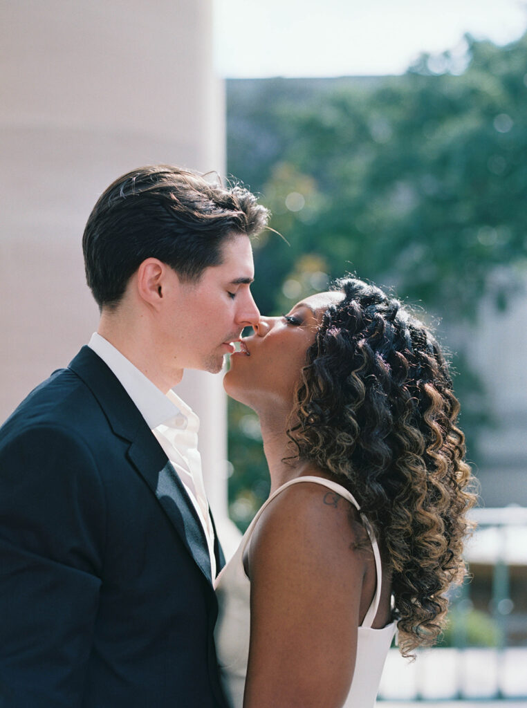 Engagement photos of a couple outside at the National Gallery of Art Museum in Washington, DC. Couple is almost kissing.