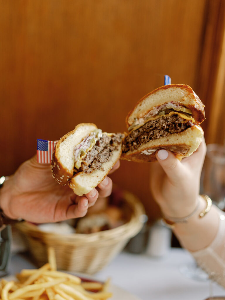 Couple cheers-ing with their cheeseburgers at Le Diplomate in Washington, DC.