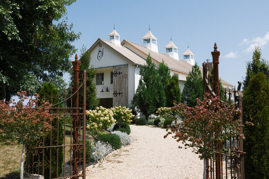 The Seclusion wedding venue with white barn, cupolas, and manicured garden entrance