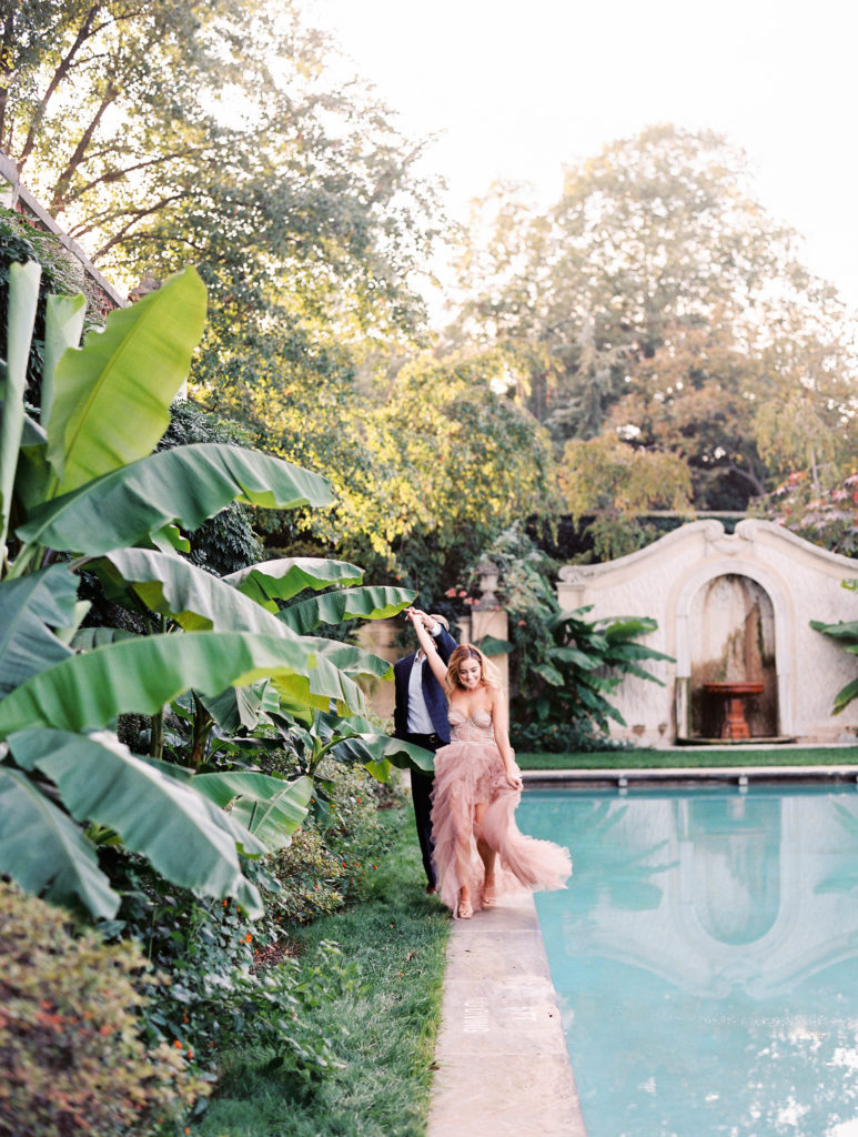 Couple running by a pool in a suit and gown.