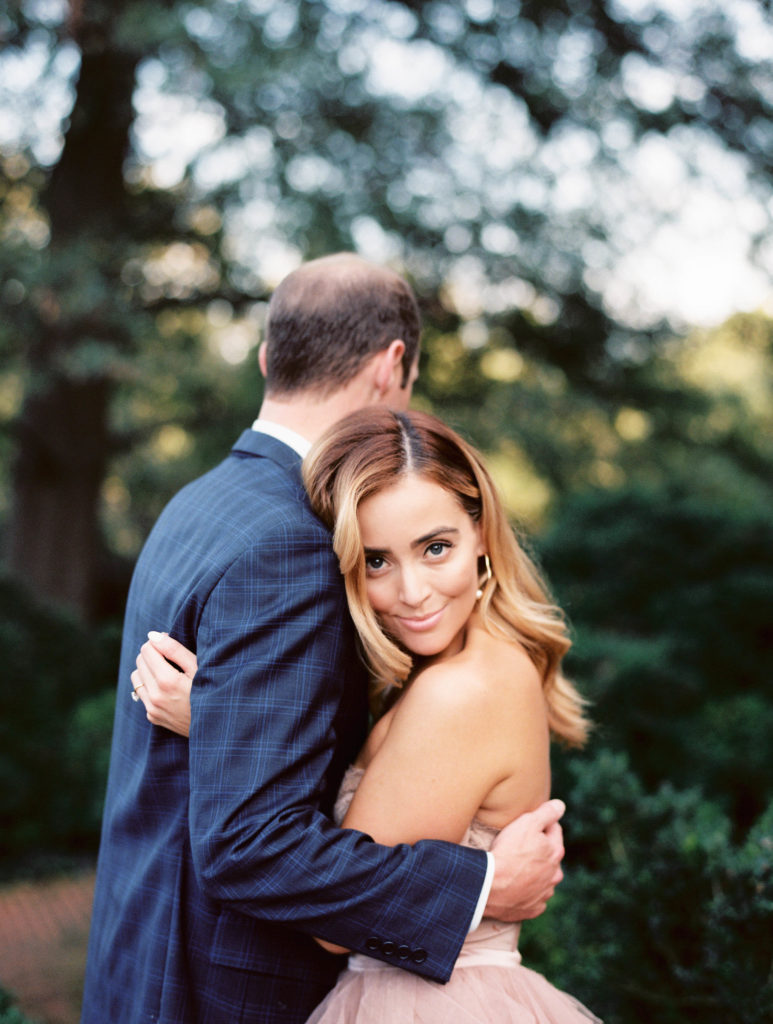Engagement photos with a couple kissing in a blush dress and plaid suit.