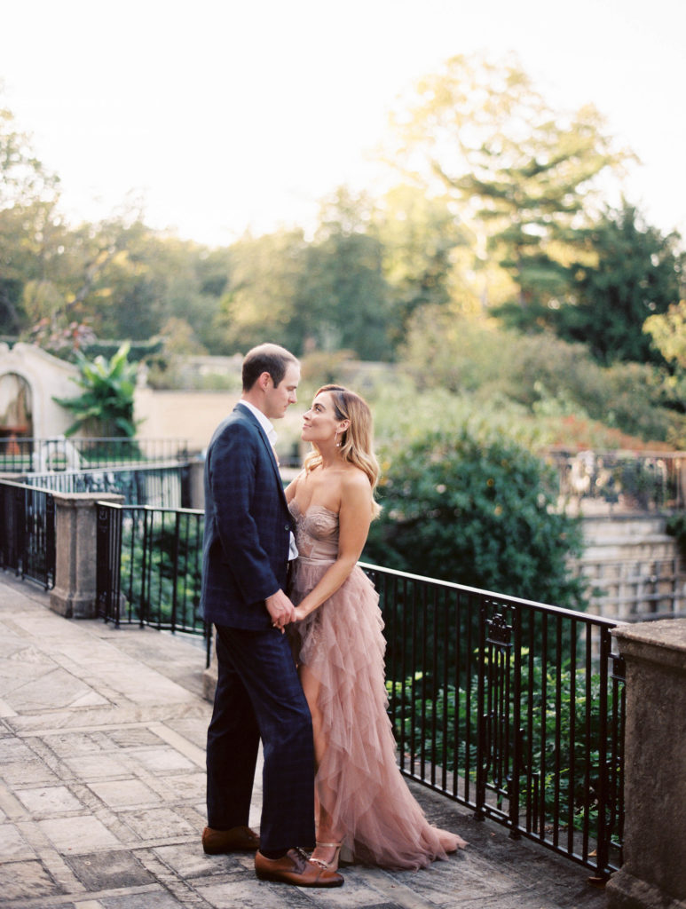 Engagement photos with a couple kissing in a blush dress and plaid suit.