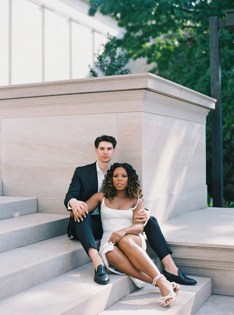 Engagement photos of a couple outside at the National Gallery of Art Museum in Washington, DC. Couple is sitting on the steps.
